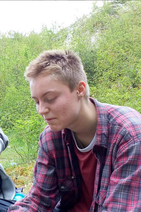 17 year old white trans guy wearing a plaid red shirt outdoors