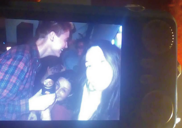 photo of a small digital camera screen with an overexposed photo of a party, jay is holding a can and everyone is smiling and in a heap