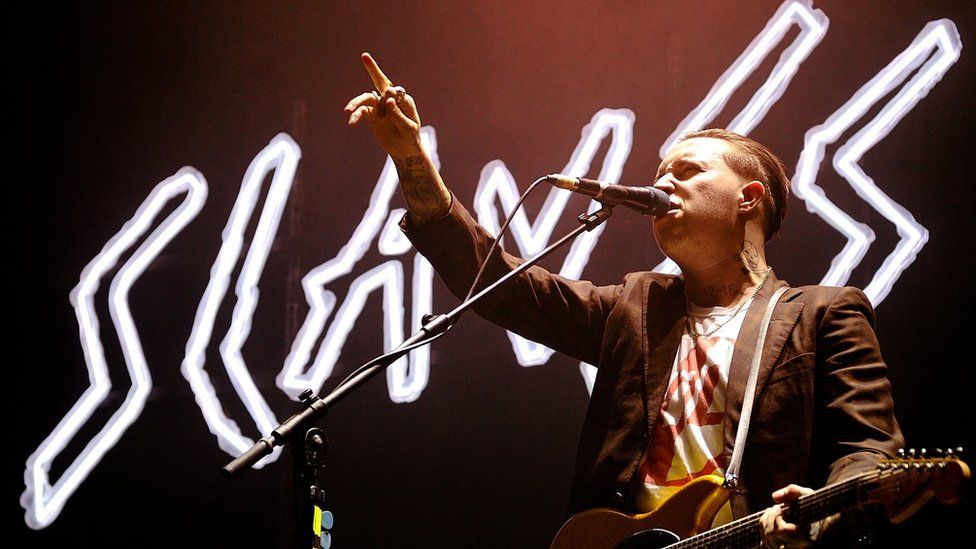 slaves logo with singer in front of it