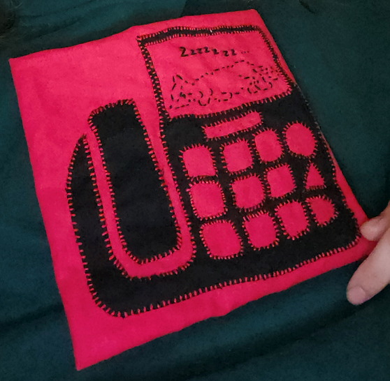 Red fabric with a black applique fax machine. An ASCII cat is sleeping on the page.