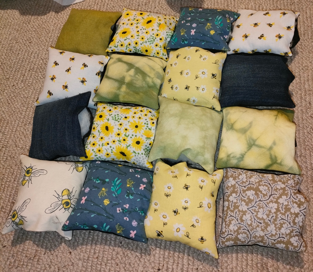 16 green, yellow and blue mini cushions arranged in a patchwork square.