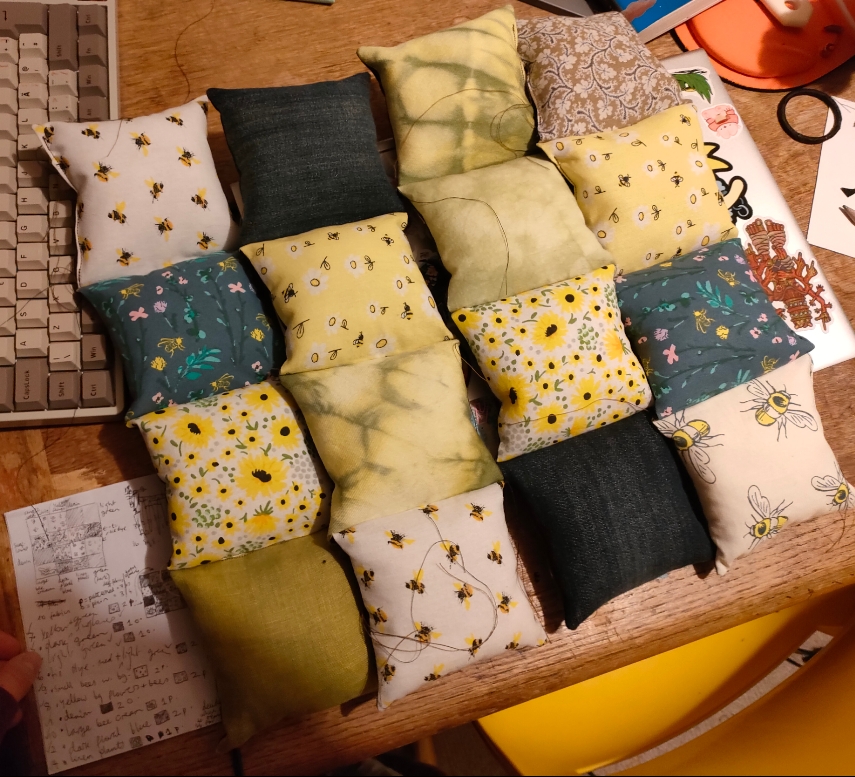 now the squares are sewn into strips of four. 16 green, yellow and blue mini cushions arranged in a patchwork square.