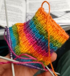 The beginning of a rainbow sock on four knitting needles.