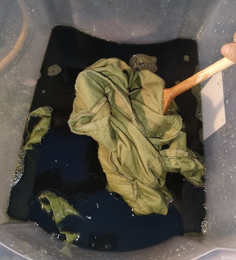 wet green fabric in dye bath.